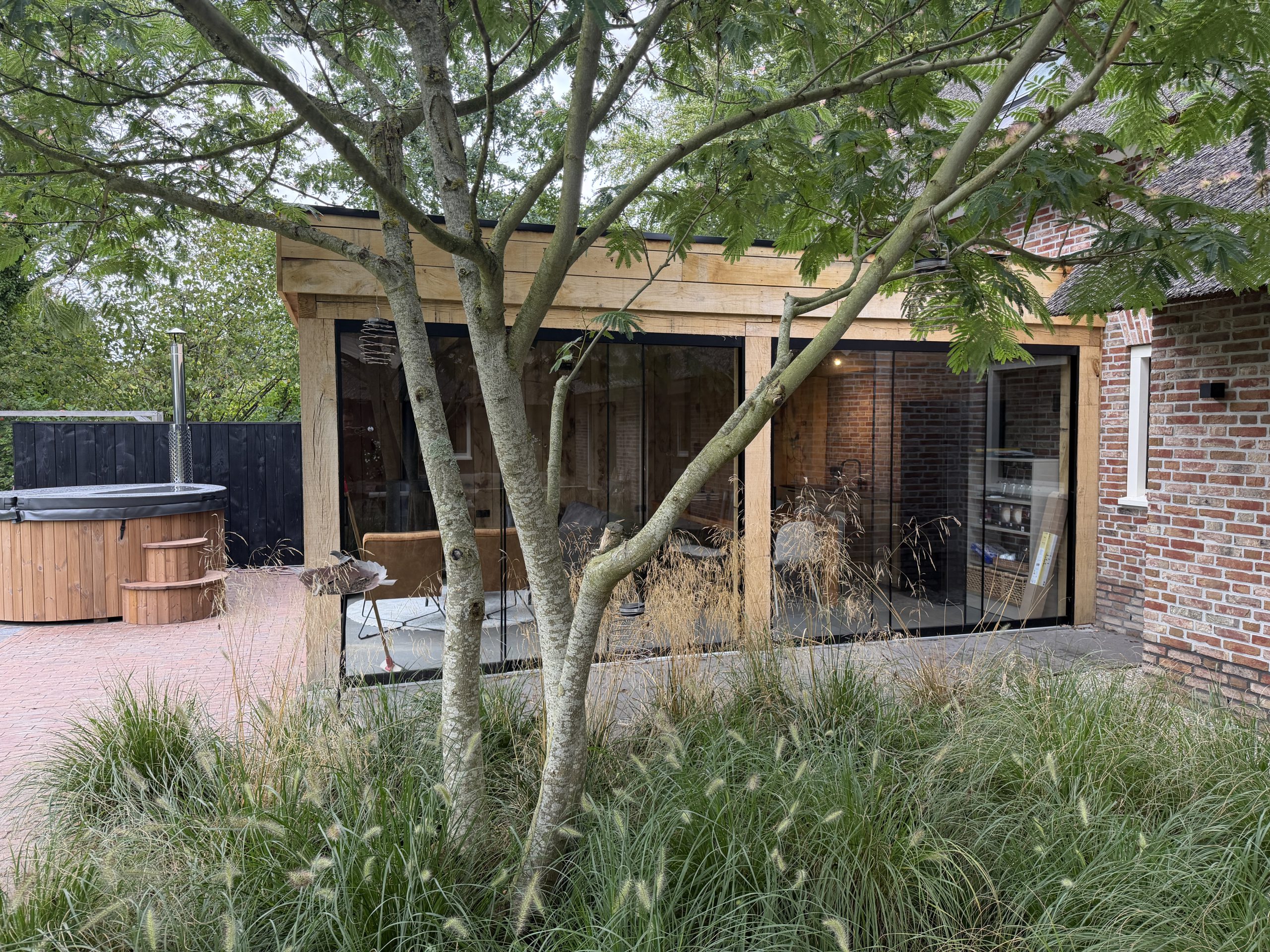 Maatwerk houten tuinkamer met glaswanden en beplanting in Gees