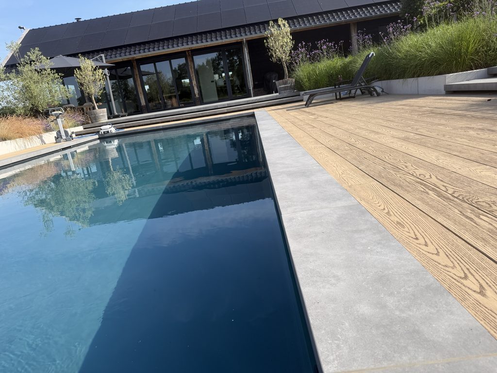 Zwembad met natuurstenen rand, Millboard-vlonders en tuinkamer in IJhorst