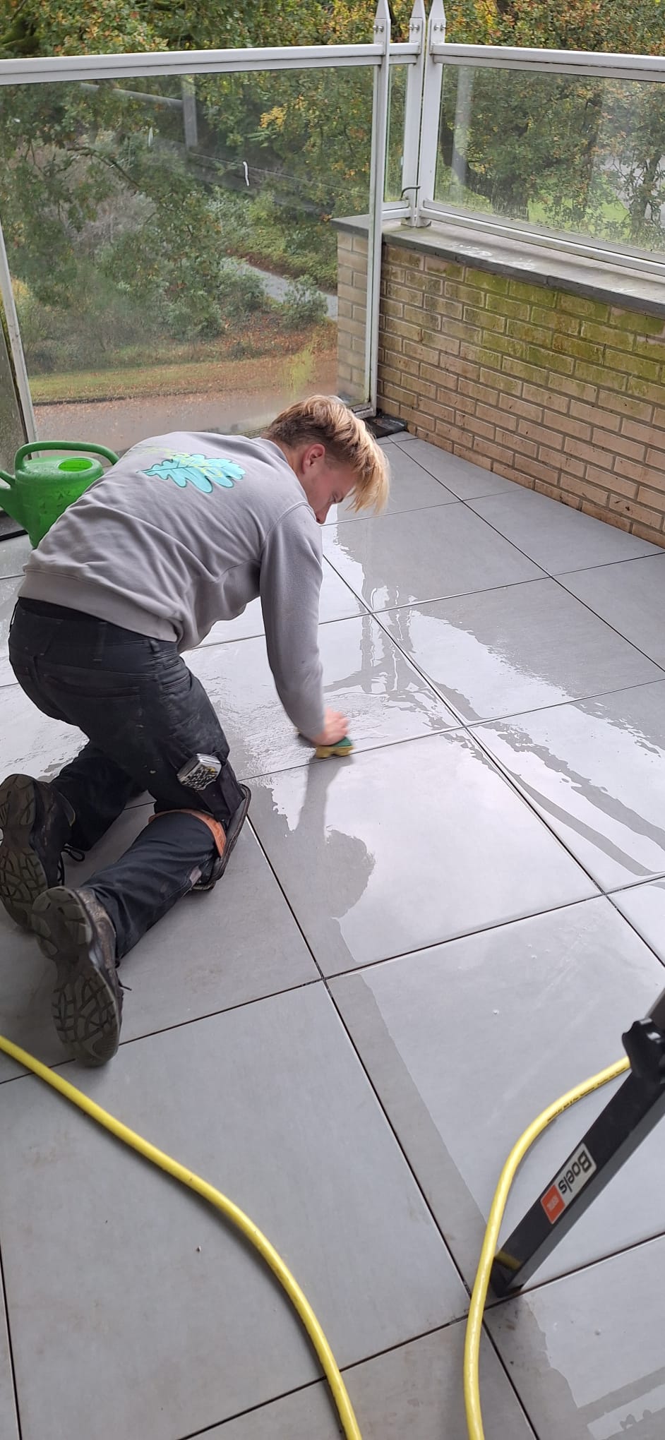 Curatio medewerker reinigt de voegen van het nieuwe dakterras