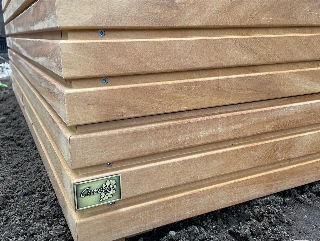 Detail van maatwerk houten plantenbak met Curatio beeldmerk