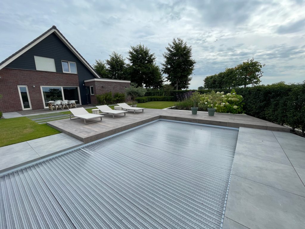 Zwembadterras met ligbedden en bloeiende beplanting