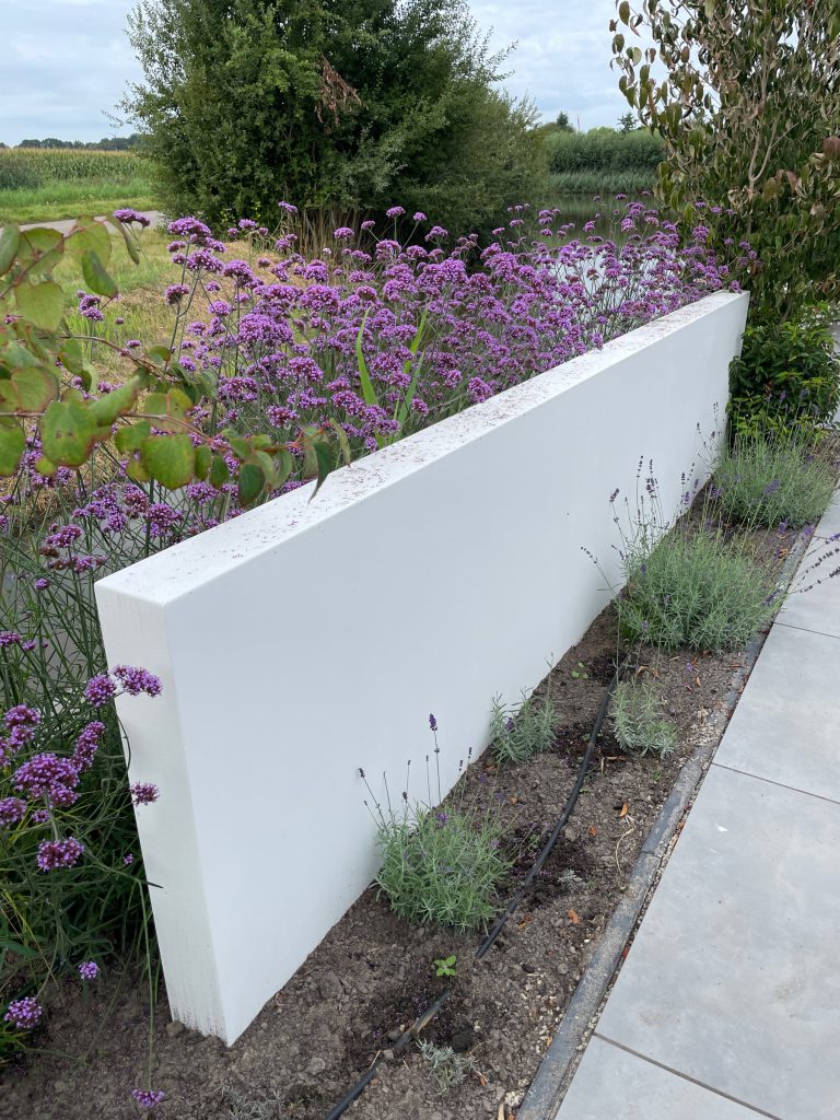 Witte tuinwand met bloeiende beplanting