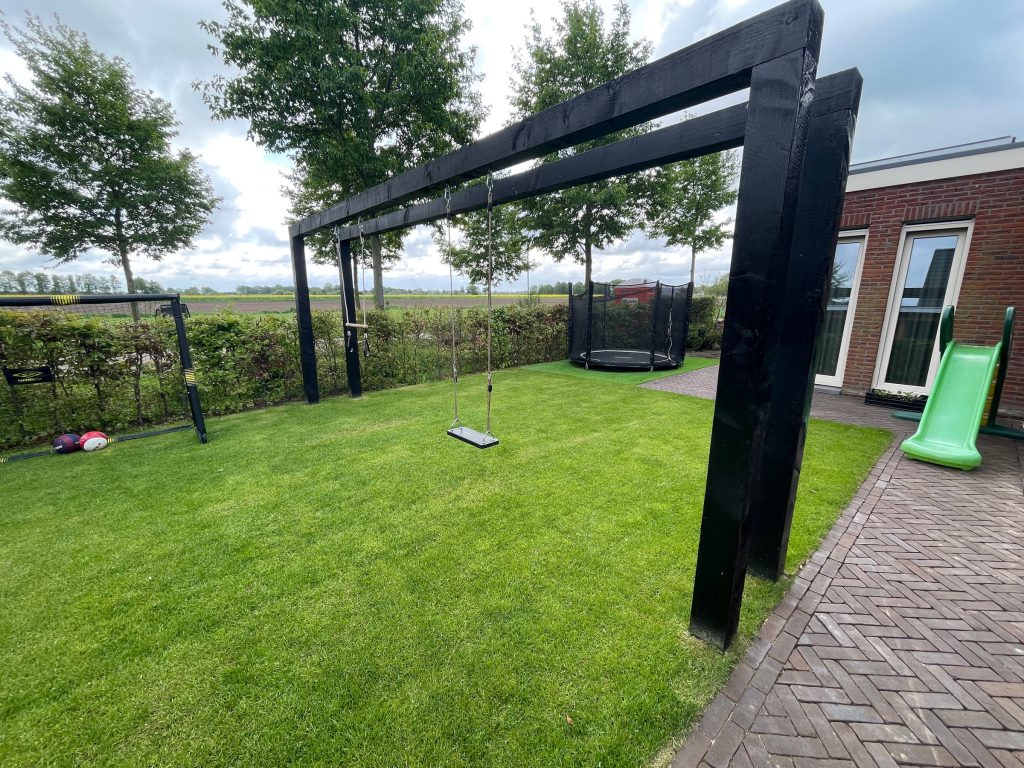 Zwarte pergola met schommel in de kindertuin