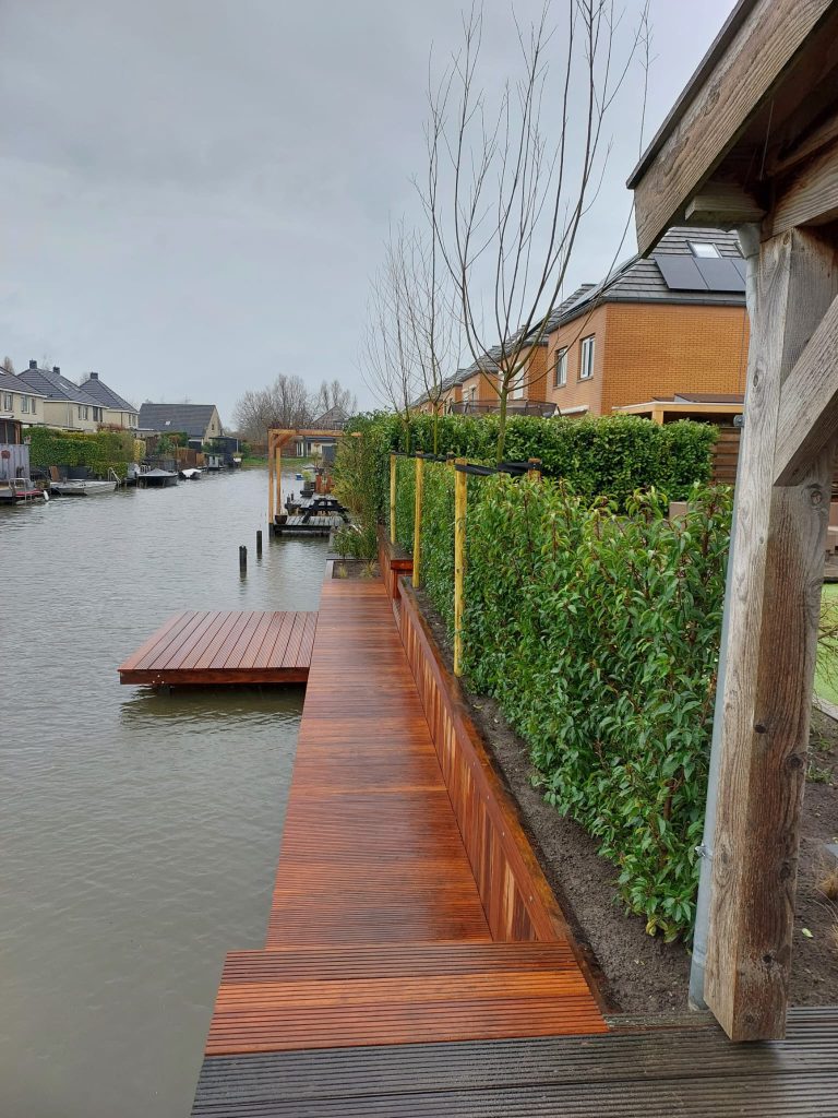 Houten vlonder en steiger langs een groene tuin aan het water