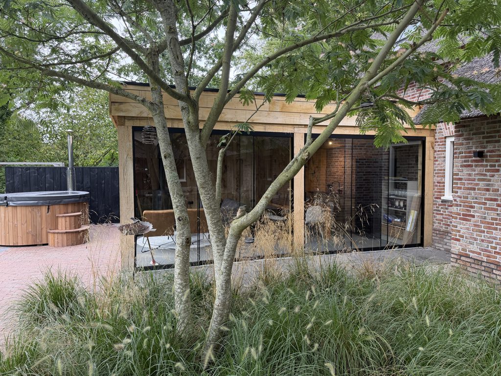 Maatwerk tuinkamer met glazen wanden gezien vanuit de tuin in Gees