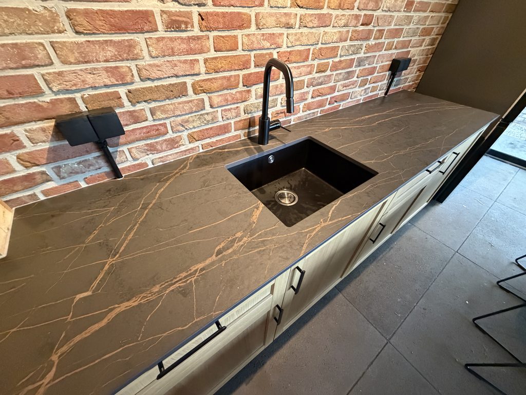 Maatwerk keuken met donkere spoelbak en zwarte kraan in de tuinkamer in Gees