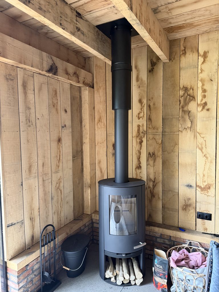 Houtkachel tegen de eikenhouten wand van de tuinkamer