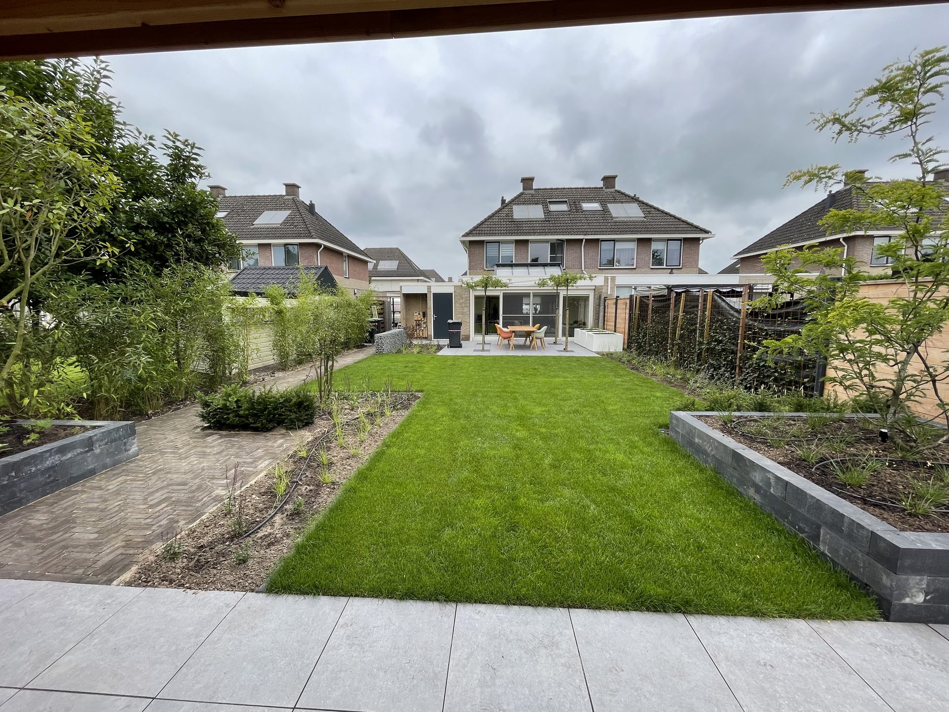 Achtertuin met nieuw gazon, borders en keramisch terras