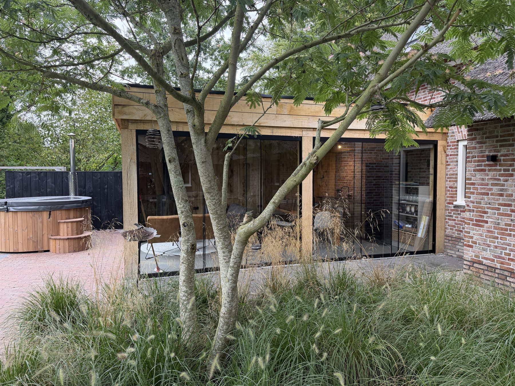 Maatwerk tuinkamer van hout en glas in een groene tuin