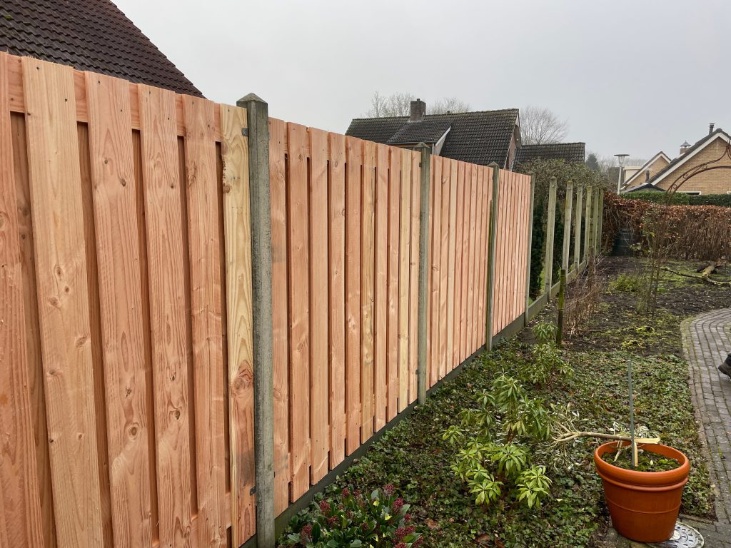 Nieuwe houten tuinafscheiding met betonpalen en betonplinten