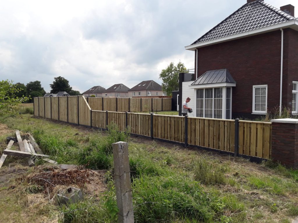 Maatwerk houten schutting met donkere staanders rond een tuin