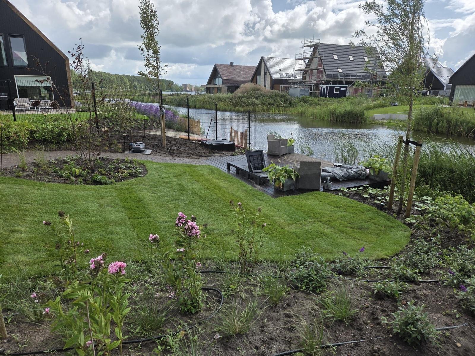 Gazon en vlonder aan het water in de moderne tuin in Zwolle
