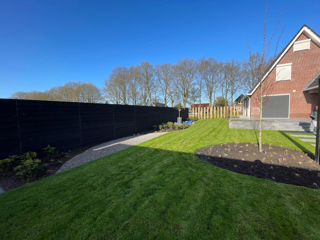 Zwarte houten tuinafscheiding langs een groene tuin