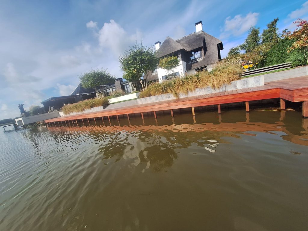 Lange Padouk vlonder langs de waterkant bij de tuin