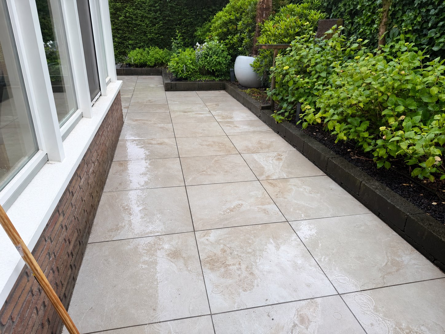 Keramisch tuinpad langs de woning en groene borders in Ommen