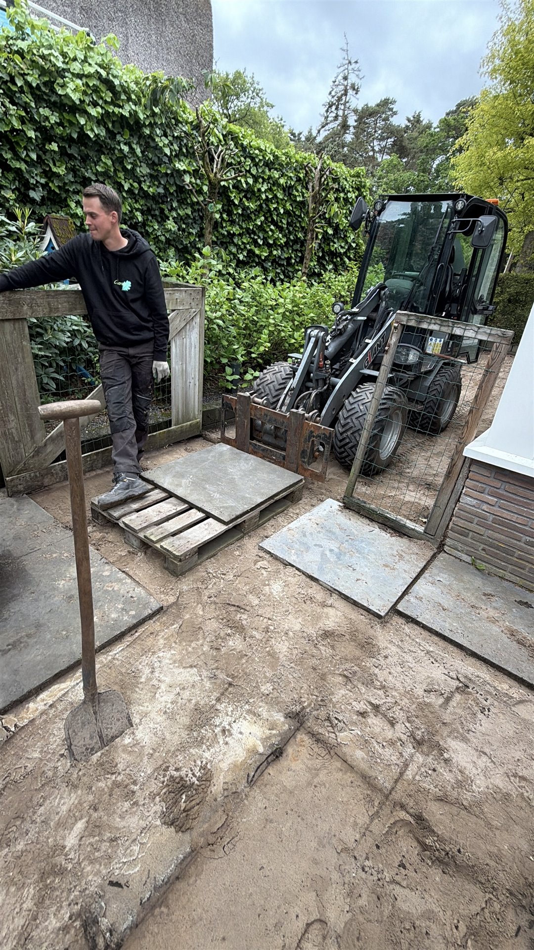 Verwijderen van oude terrastegels met een shovel in Ommen